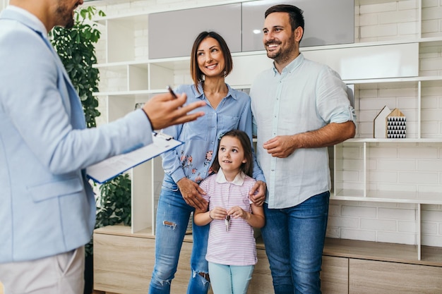 Gelukkige familie praten met makelaar over het kopen van een nieuw huis.