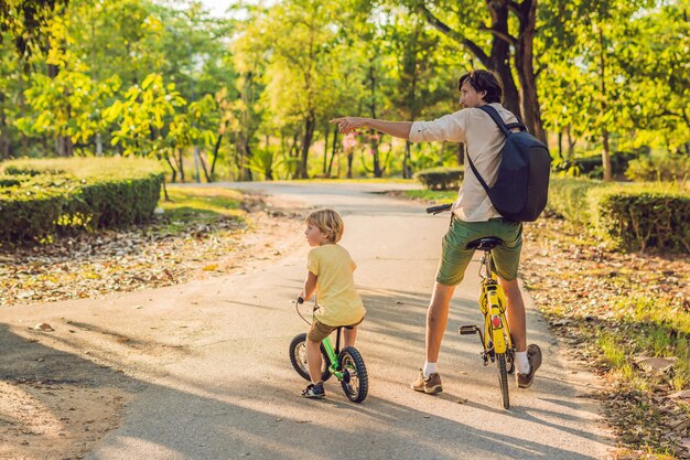 Gelukkige familie rijdt buiten fietsen en glimlacht. Vader op een fiets en zoon op een loopfiets.