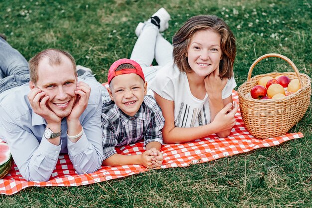 Foto gelukkige familie rust in de natuur. moeder, vader en kind genieten en liggend op geruite plaid in weide