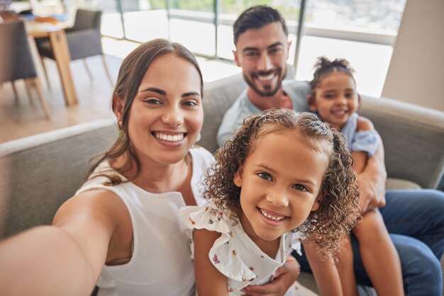 Gelukkige familie selfie en liefde op de bank in huis woonkamer bank hechten en verzorgen Portret moeder en vader kinderen of meisjes uit Spanje quality time doorbrengen in ontspannen zorg en ondersteuning in huis