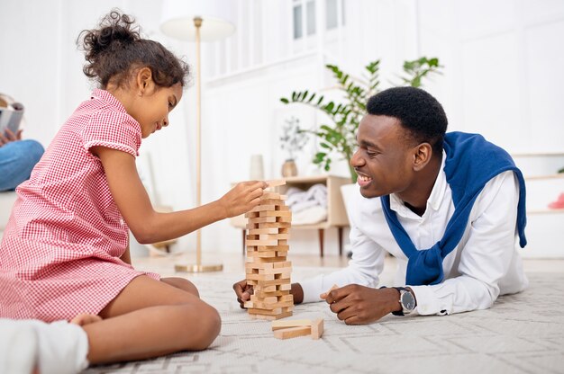 Gelukkige familie speelspel in de woonkamer. moeder, vader en hun dochtertje poseren samen thuis, goede relatie. mama, papa en vrouwelijk kind, fotoshoot in huis