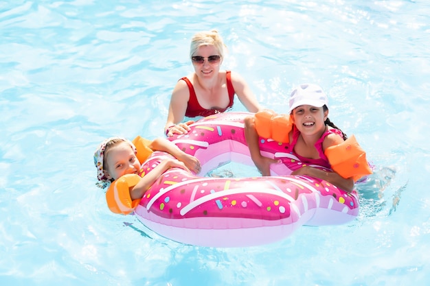 Gelukkige familie spelen in blauw water van zwembad op een tropisch resort aan zee. Zomer vakanties concept.