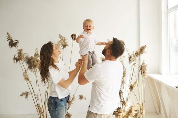 Gelukkige familie spelen thuis met hun kind op een witte achtergrond met riet
