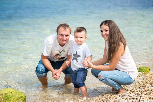 Gelukkige familie staande op een houten ponton voor de zee in de zomer