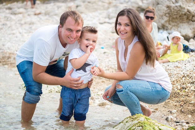 Gelukkige familie staande op een houten ponton voor de zee in de zomer