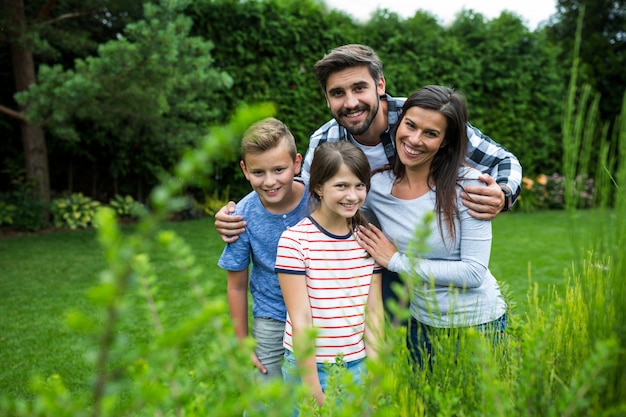 Gelukkige familie staande op gras in park op een zonnige dag