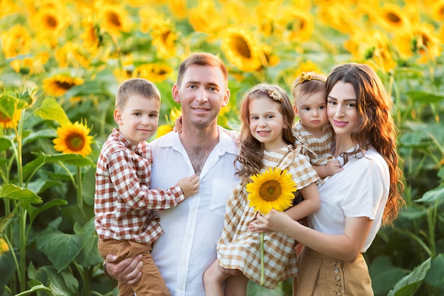 Gelukkige familie, vader, dochter en zoon hebben plezier, spelen tussen bloeiende zonnebloemen in de frisse lucht