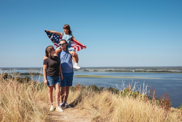 Gelukkige familie vader moeder en dochter met amerika vlag op de natuur