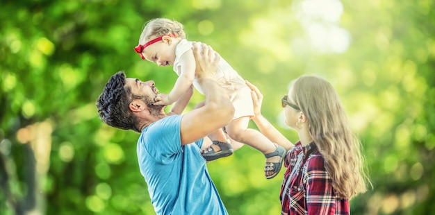 Gelukkige familie, vader, moeder en dochter spelen in het park en genieten van een zonnige zomerdag.