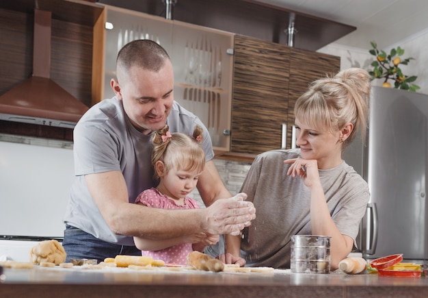 Gelukkige familie, vader, moeder en dochtertje bereiden samen heerlijke paaskoekjes in de huiskeuken. voorbereiden op gezinsvakanties