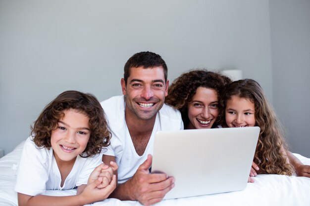 Gelukkige familie van familie die laptop samen op bed met behulp van