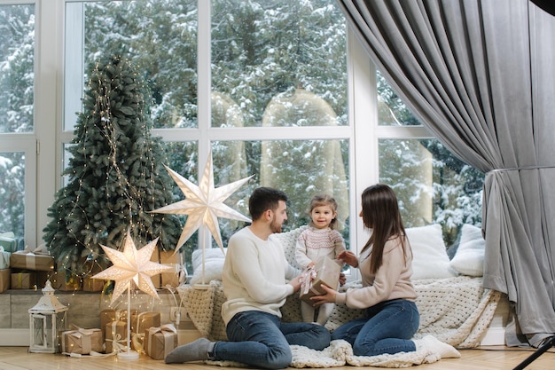 Gelukkige familie van moeder, vader en dochtertje brachten samen tijd door aan de vooravond van Kerstmis jong