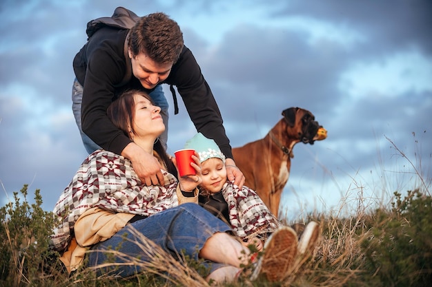 gelukkige familie van reizigers, een man bedekt met een deken en knuffelt zijn vrouw en dochter in de natuur