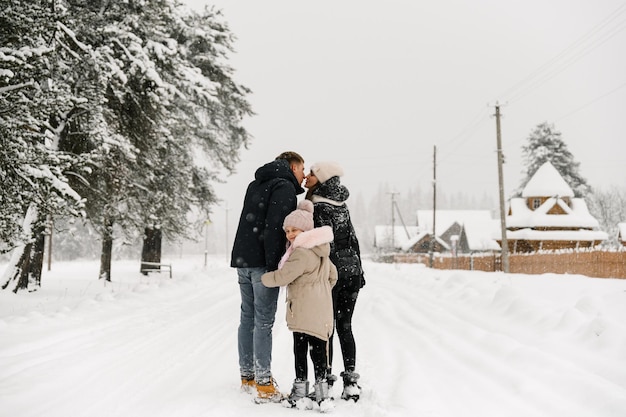 Gelukkige familie veel plezier in het winterbos. moeder, vader en dochter spelen met sneeuw. genieten van tijd samen doorbrengen. familie concept