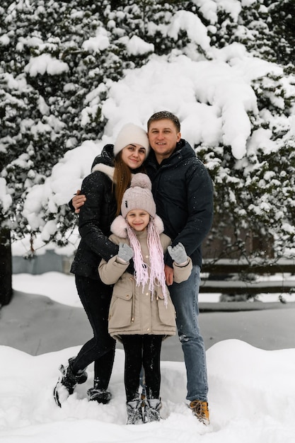 Gelukkige familie veel plezier in het winterbos. Moeder, vader en dochter spelen met sneeuw. Genieten van tijd samen doorbrengen. Familie concept