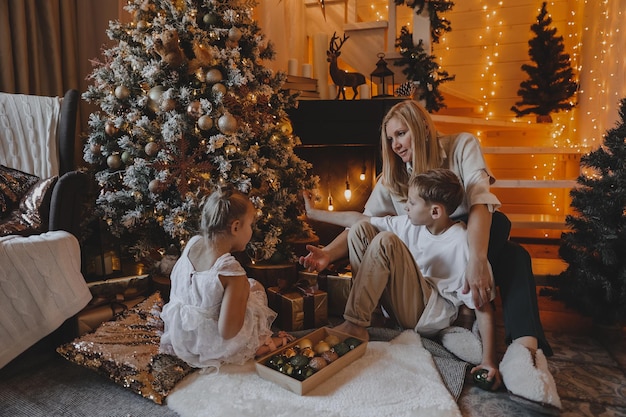 Gelukkige familie versieren een kerstboom met boubles en cadeautjes in de woonkamer