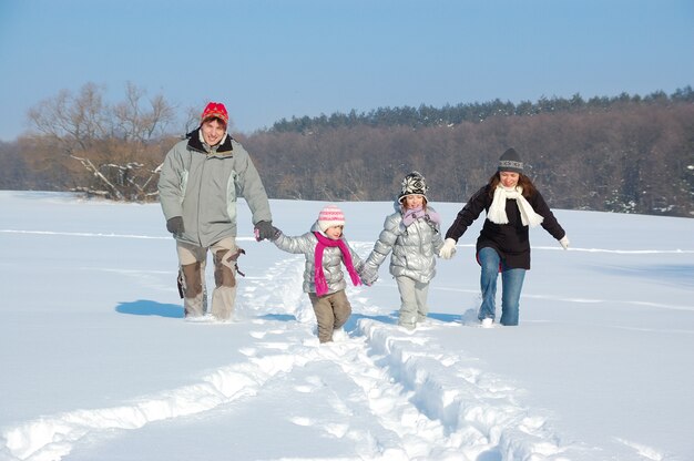 Gelukkige familie wandelingen in de winter, plezier maken en buiten spelen met sneeuw op vakantie weekend