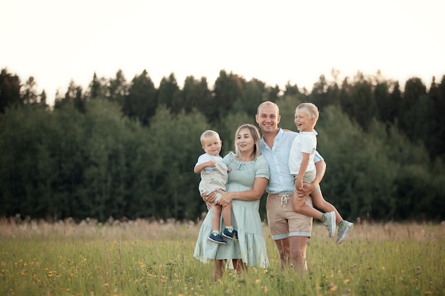 Foto gelukkige familie wandelingen in het veld in de zomerpret bij zonsondergang