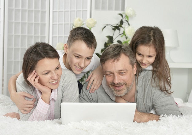 Gelukkige familie zit met laptop thuis