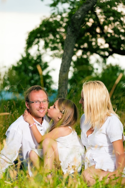 Gelukkige familie zitten in de weide