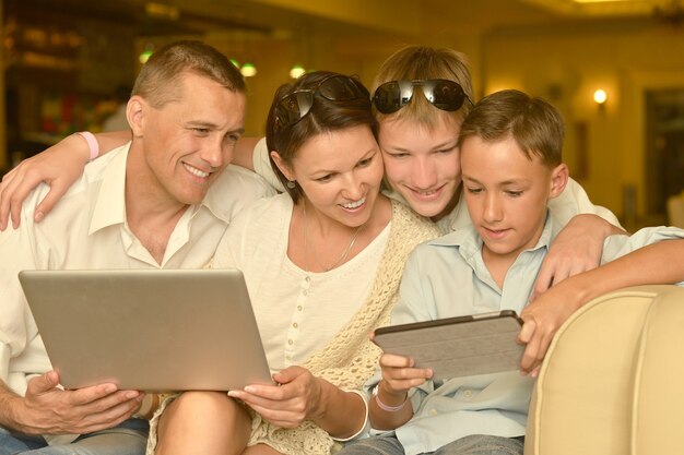 Gelukkige familie zitten met laptop en tablet pc