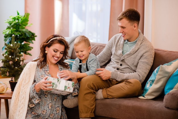 Gelukkige familie zittend op de bank en uitpakken presenteert