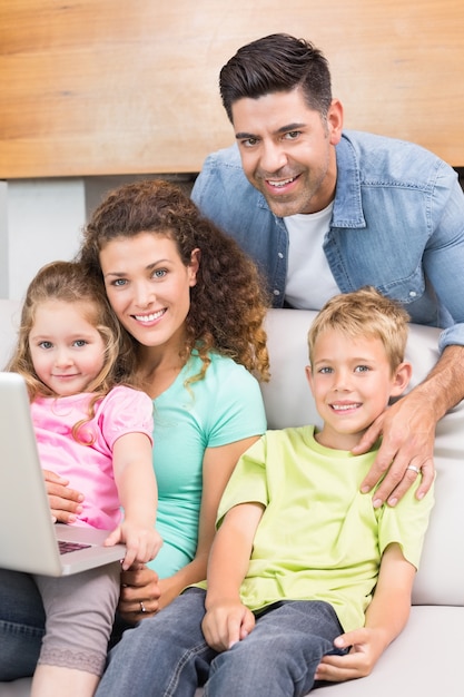 Gelukkige familie zittend op de Bank met behulp van laptop