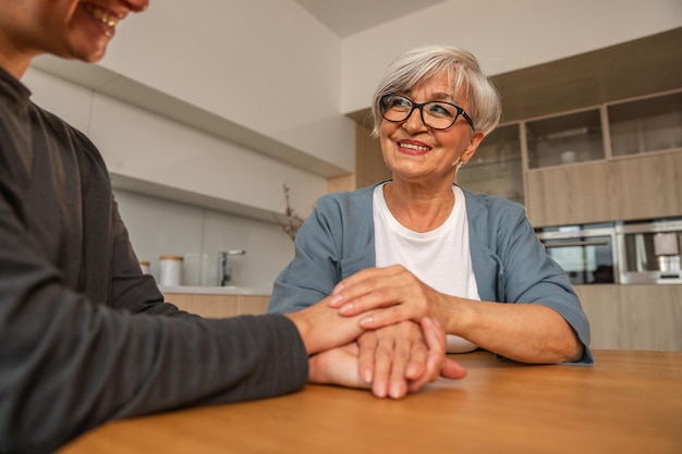 Gelukkige familie zorgzame volwassen dochter die handen vasthoudt liefhebbende oudere vrouw moeder jonge vrouw met moeder