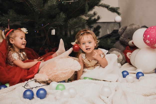 Gelukkige familiekinderen die nieuwjaar en kerstmis vieren bij versierde kerstboom en slingers