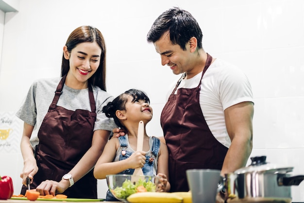 Gelukkige familievader en moeder met dochter die en maaltijd samen in de keuken koken voorbereiden