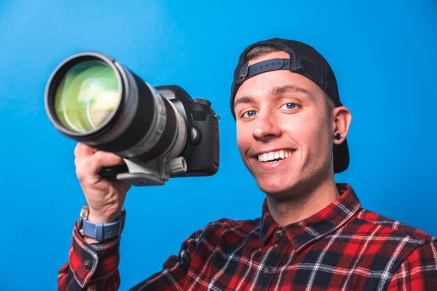 Foto gelukkige fotograaf die foto's maakt en zijn camera controleert in een studio die schiet als content creator