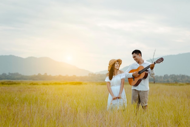 Gelukkige geliefden staan op het grasland elkaar teder aan te kijken. Mannen spelen gitaar, vrouwen luisteren. Ze kijken elkaar liefdevol en lachend aan.