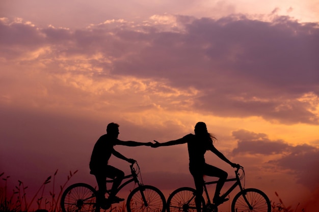 Gelukkige gezinnen fietsen op het strand en genieten van het zonsondergang.