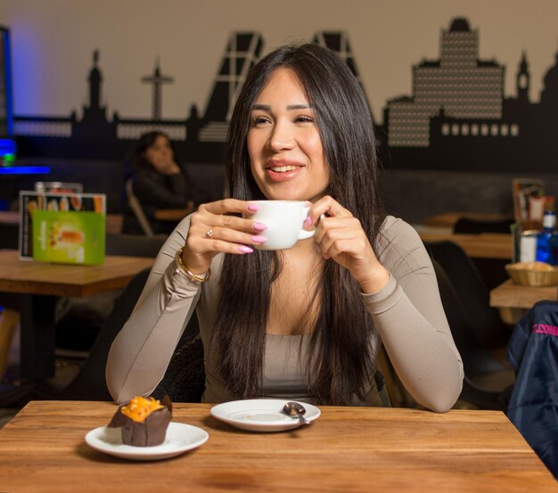 Gelukkige glimlach en koffie winkel jonge vrouw geniet van een kop koffie en dessert in een restaurant