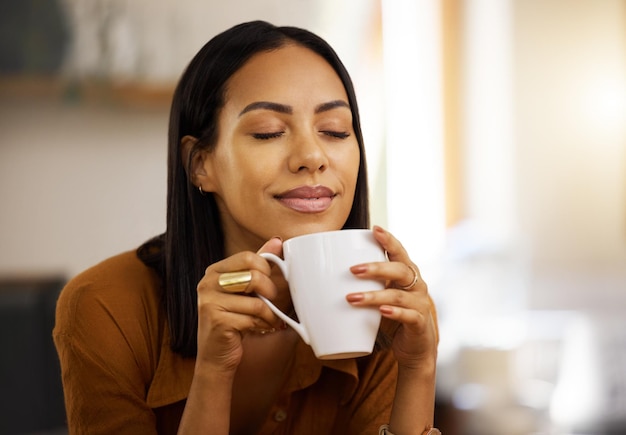 Gelukkige glimlach koffie en vrouw thuis in een keuken met een warm drankje gevoel ontspannen en kalm in de ochtend Geluk zen en jonge vrouw in een huis met thee en mok in een huishouden met mockup