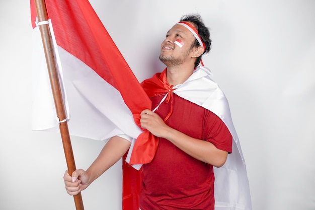 Foto gelukkige glimlachende indonesische man met de vlag van indonesië39 om de onafhankelijkheidsdag van indonesie te vieren geïsoleerd op een witte achtergrond
