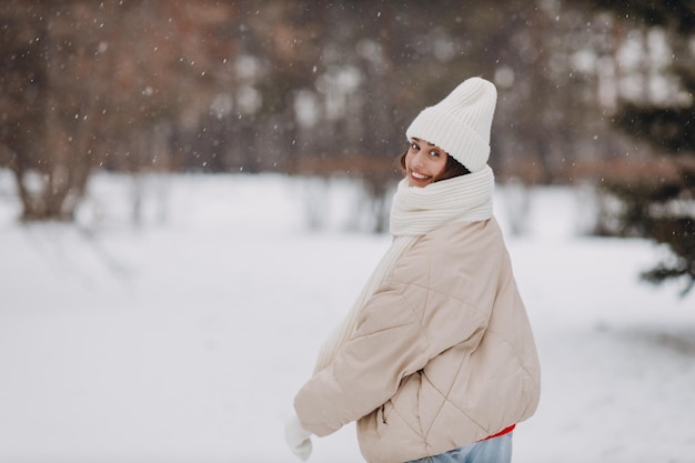 Gelukkige glimlachende jonge vrouw portret gekleed jas sjaal hoed en handschoenen geniet van het winterweer in het besneeuwde winterpark