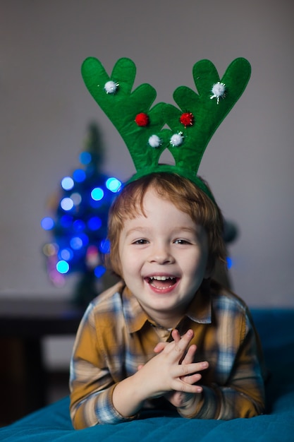 gelukkige glimlachende jongen in een nieuwjaarskostuum van een hert dat Kerstmis en Nieuwjaar viert