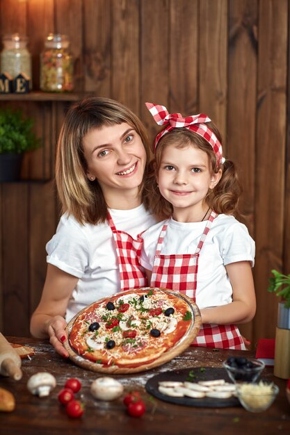 Gelukkige glimlachende moeder en dochter met gekookte pizza