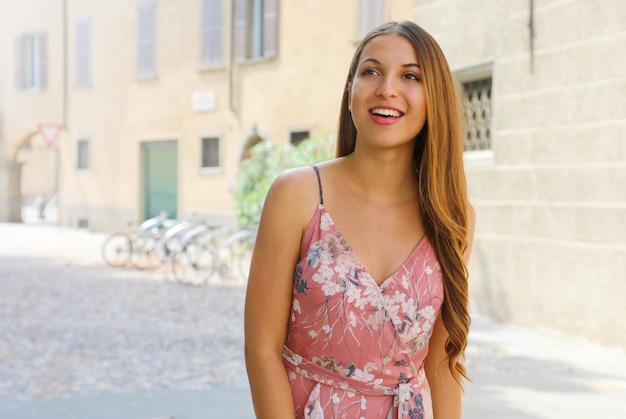 Gelukkige glimlachende mooie jonge vrouw die in oude Italiaanse stad loopt die aan de kant kijkt.