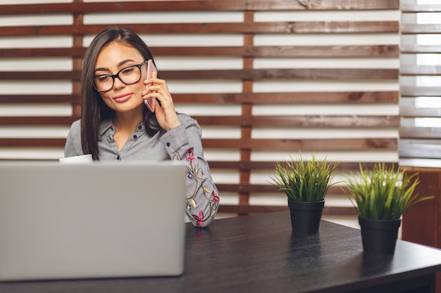 Gelukkige glimlachende vrouw die met laptop en het drinken koffie werkt