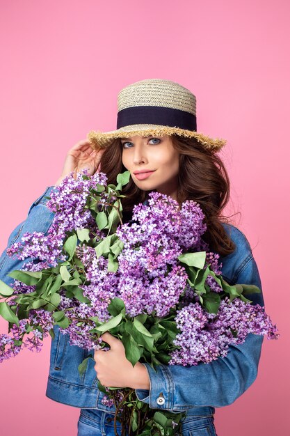 Gelukkige glimlachende vrouw die over geur van boeket lilac bloemen over genieten