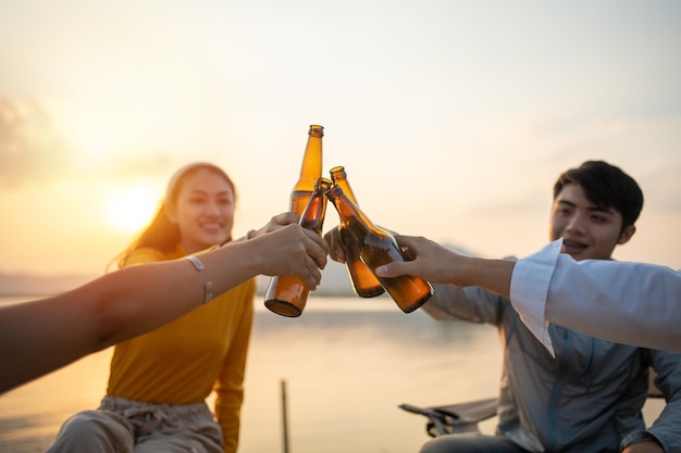 Gelukkige groep aziatische vrienden gitaar spelen en zingen genieten van kamperen en bier drinken