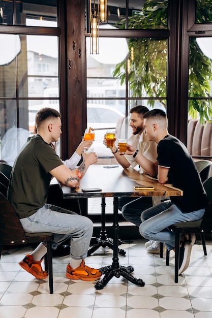 Gelukkige groep vrienden die drinken en rammelen met bier en cocktails in het restaurant van de brouwerijbar Dranklevensstijlconcept met jongens en meisjes die samen plezier hebben