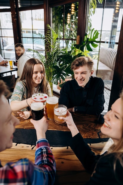 Gelukkige groep vrienden die drinken en rammelen met bier en cocktails in het restaurant van de brouwerijbar Dranklevensstijlconcept met jongens en meisjes die samen plezier hebben