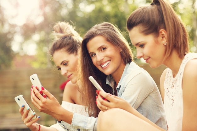 Foto gelukkige groep vrienden met smartphones die buiten zitten