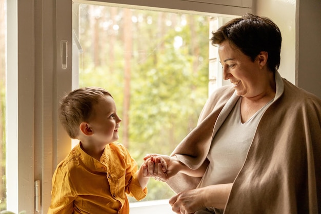 Gelukkige grootmoeder en kleinzoon genieten samen van tijd Positieve vrouw van middelbare leeftijd die tijd doorbrengt met klein schattig kleinkind 50-jarige oma met kleinkind Multigenerationele familie