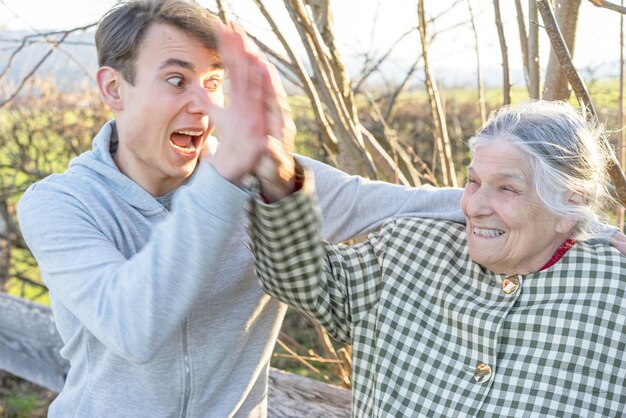 Foto gelukkige grootmoeder geeft high five met kleinzoon op het veld