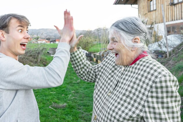 Gelukkige grootmoeder geeft high five met kleinzoon op het veld