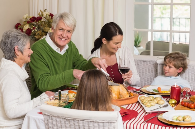 Gelukkige grootvader carving kip tijdens kerstdiner